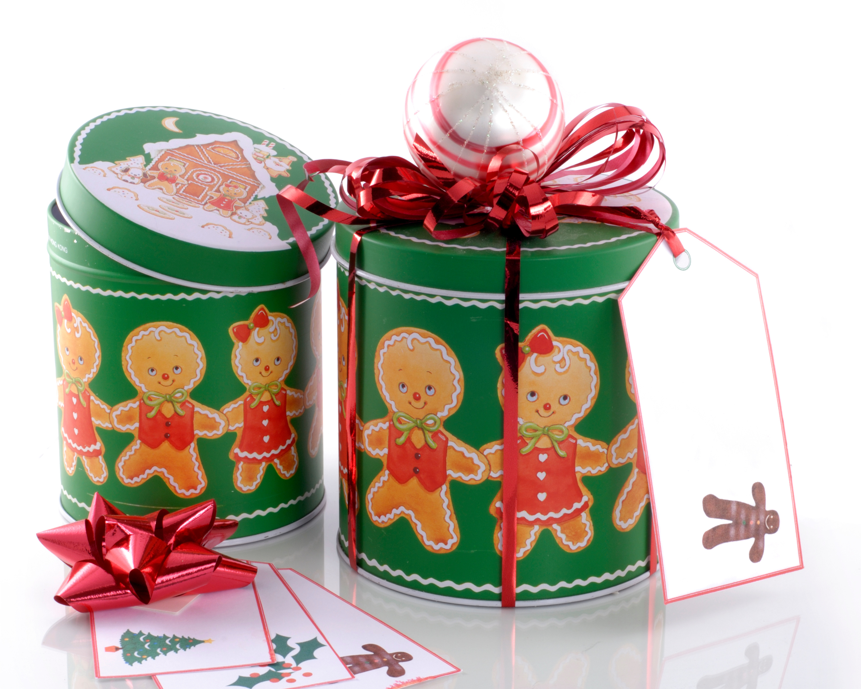 Image of a two green Christmas tins with gingerbread men on othem and some blank gift tags laying beside them.